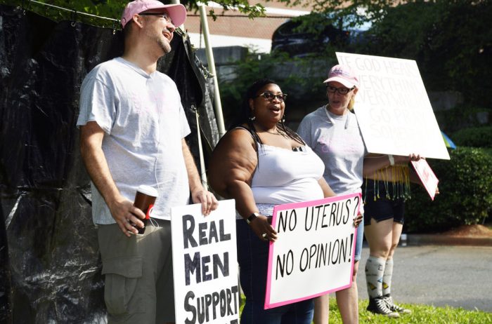 Jenevieve Hatch holds "no uterus, no opinion" sign