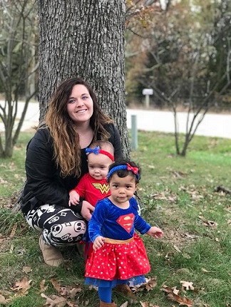Kelsey and her twin girls in super hero outfits. The girls are alive today thanks to a pregnancy resource center.