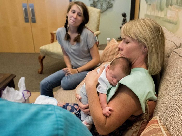 Lauren holds her new adopted baby boy as his birth mother looks on. Copyright Sara Liz Photography.