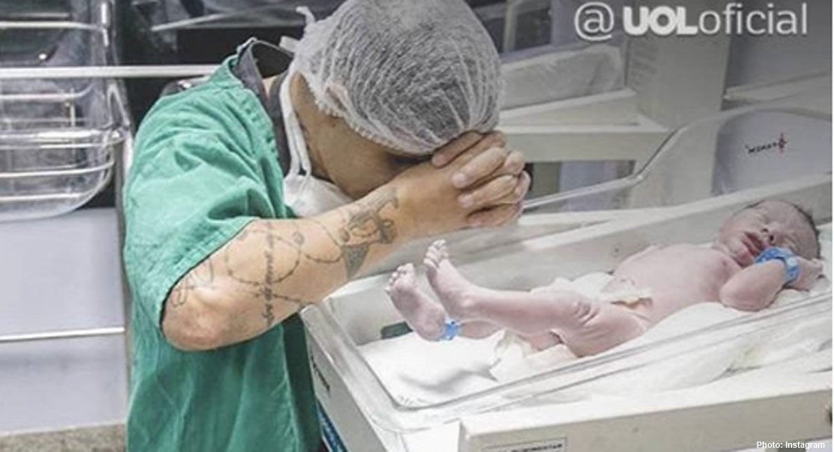 Man kneels in prayer by newborn son