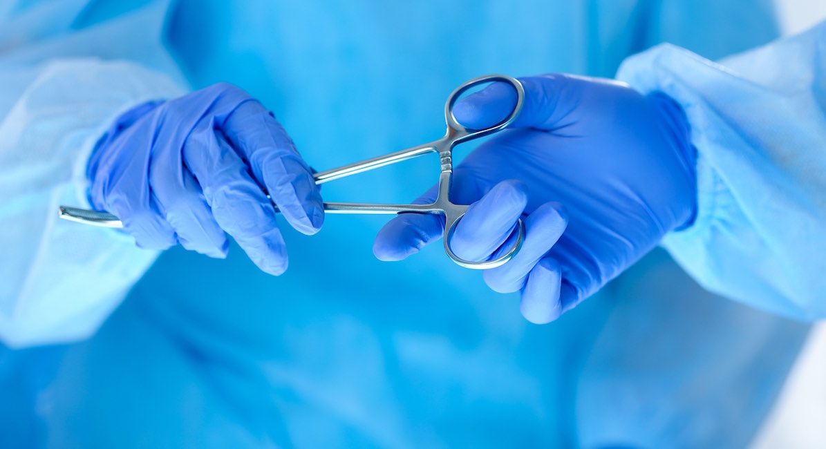 Surgeons hands holding and passing surgical instrument to other doctor