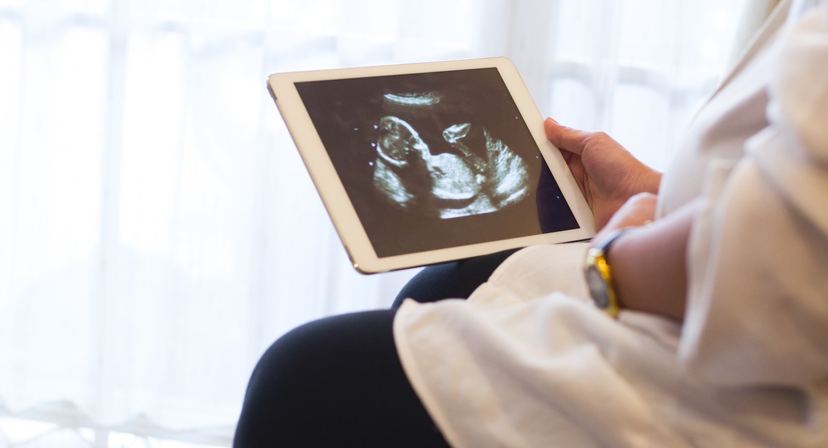 Pregnant Woman Showing Ultrasound Image On Digital Tablet