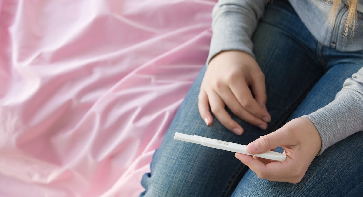 A teenage girl holding a pregnancy test