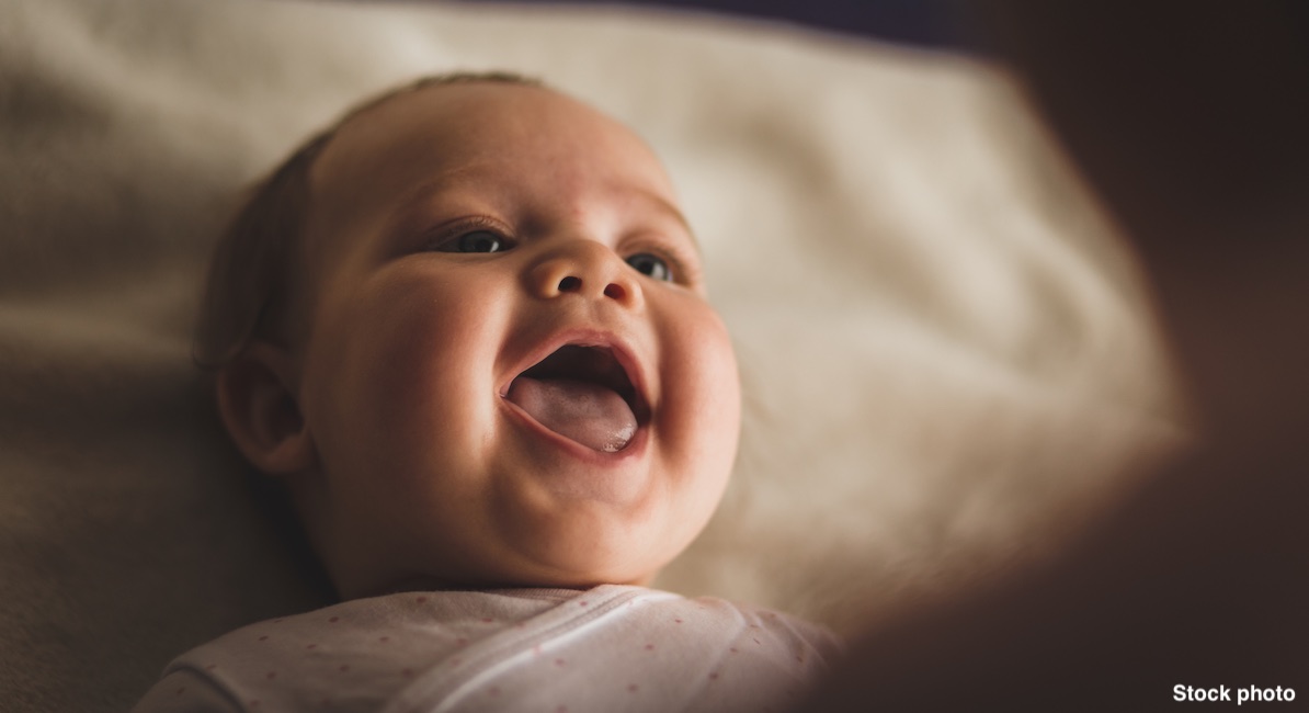 Newborn baby girl laughing and giggling while playing with her mother