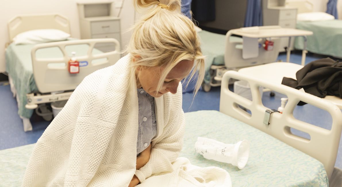 woman on hospital bed feeling sick