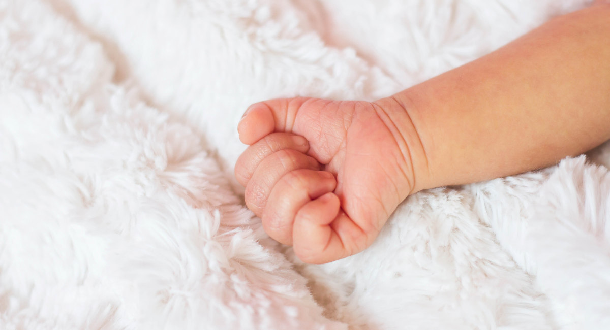 Close-Up Of Baby Hand On Bed