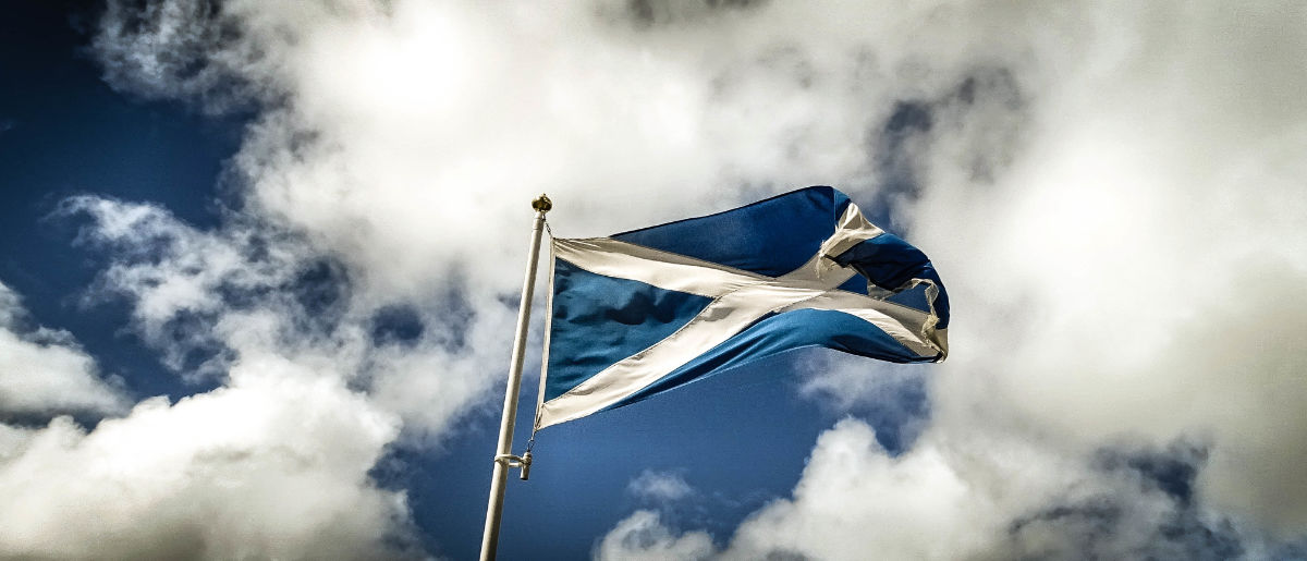Low Angle View Of Scottish Flag Waving Against Cloudy Sky
