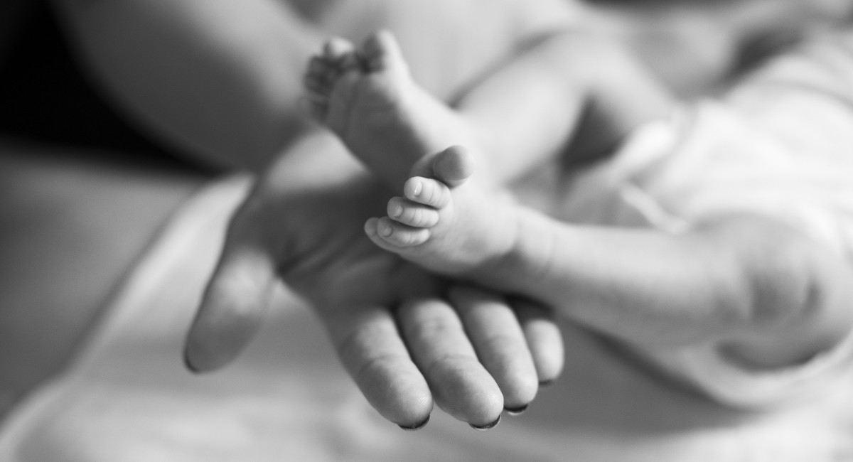 Close-up of baby’s feet in mother’s hands