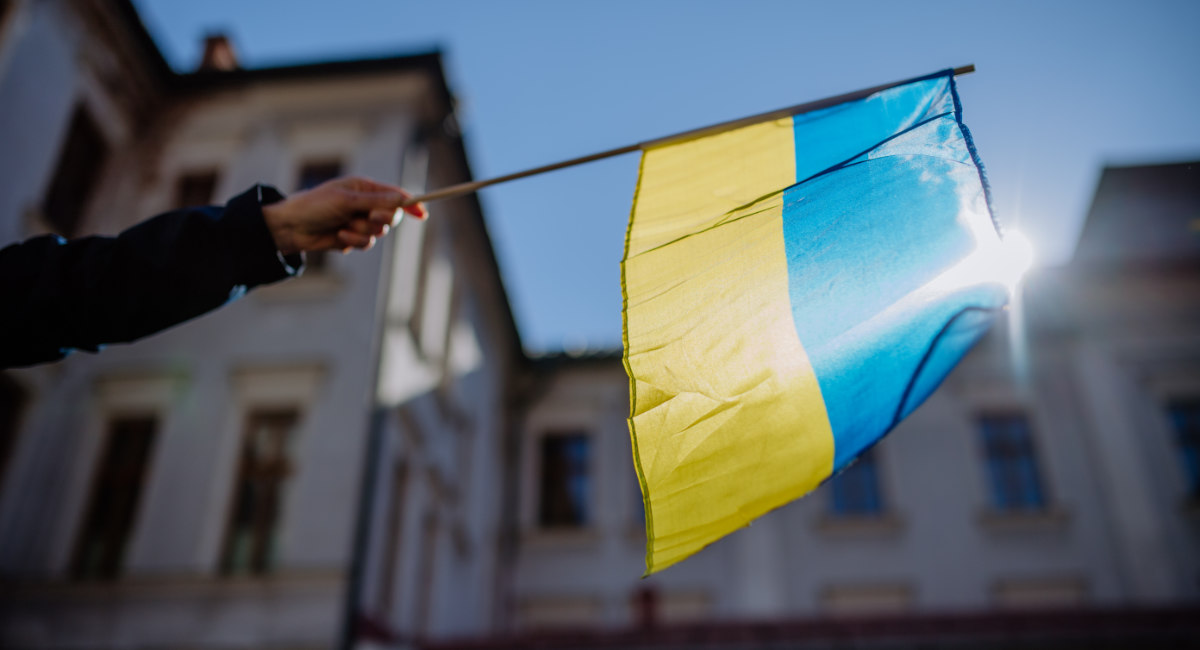 People holding Ukrainian flag and protesting against Russian invasion in Ukraine in streets.