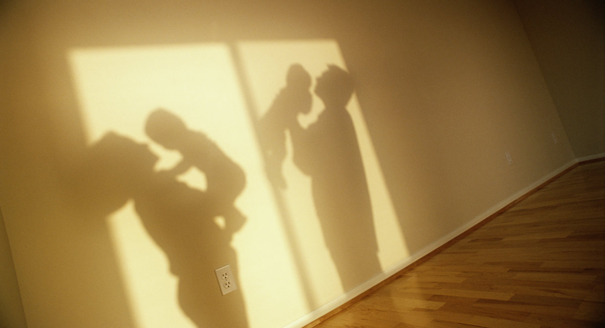 SHADOWS OF PARENTS HOLDING BABIES IN EMPTY ROOM